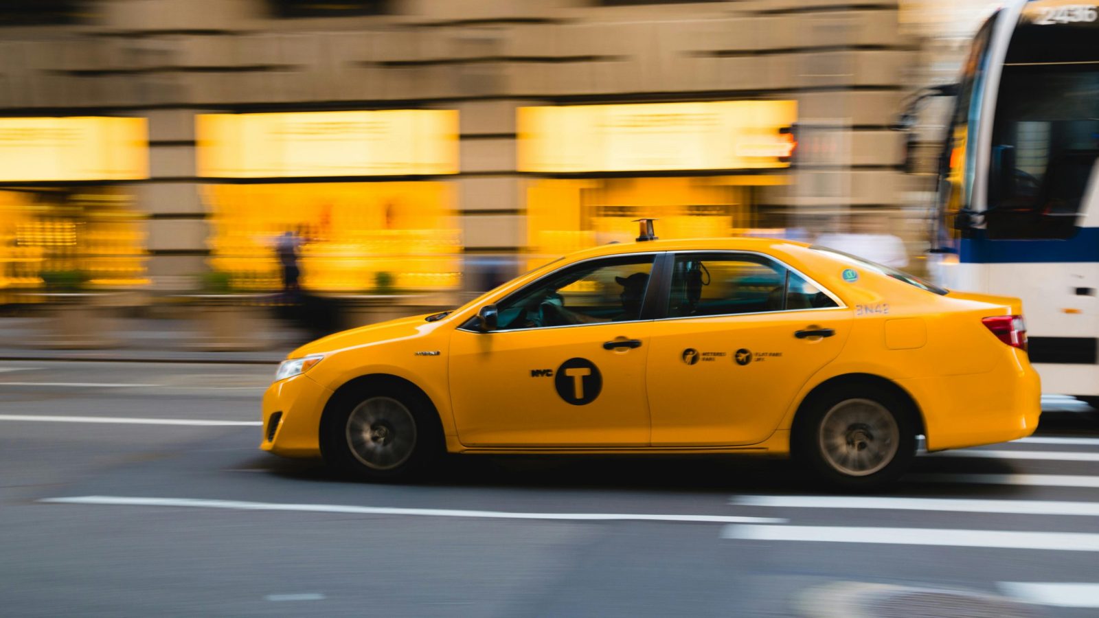 A New York City yellow taxi speeds through urban streets, capturing the bustle of city life.